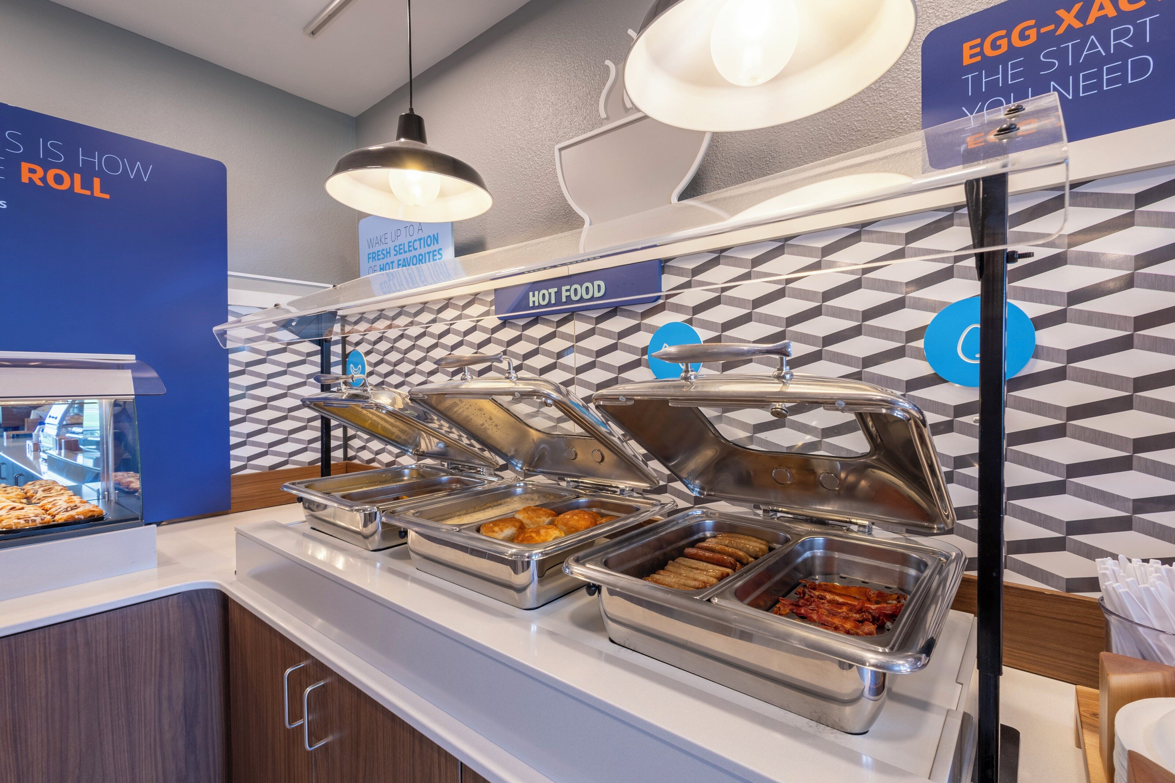 A buffet area with various food options, a sign indicating 'HOT FOOD', and a 'WAKE UP TO A FRESH SELECTION' sign.