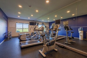 A fitness center with treadmills, elliptical machines, and a water dispenser.