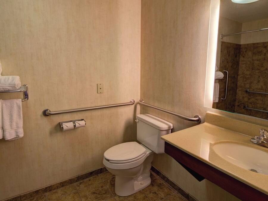 Un baño con inodoro, lavamanos, espejo y toallero.