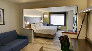 A hotel room with a bed, a sofa, a desk, and a large window. - Holiday Inn Express & Suites Sioux Center by IHG (Sioux Center)