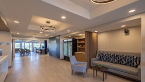 A modern lobby with a reception desk, seating area, and a refrigerator stocked with beverages. - Holiday Inn Express & Suites Sioux Center by IHG (Sioux Center)