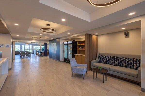 A modern lobby with a reception desk, seating area, and a refrigerator stocked with beverages. - Holiday Inn Express & Suites Sioux Center by IHG (Sioux Center)
