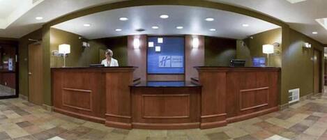 Un mostrador de recepción con una pantalla digital que muestra un logotipo, una recepcionista y un suelo de baldosas.
