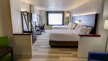 Quarto de hotel com cama, escrivaninha, cadeira e uma grande janela.