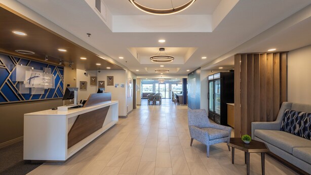 A hotel lobby with a reception desk, seating area, and a view of the outside. - Holiday Inn Express & Suites Sioux Center by IHG (Sioux Center)