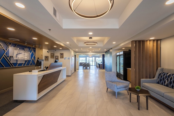 A hotel lobby with a reception desk, seating area, and a view of the outside.
