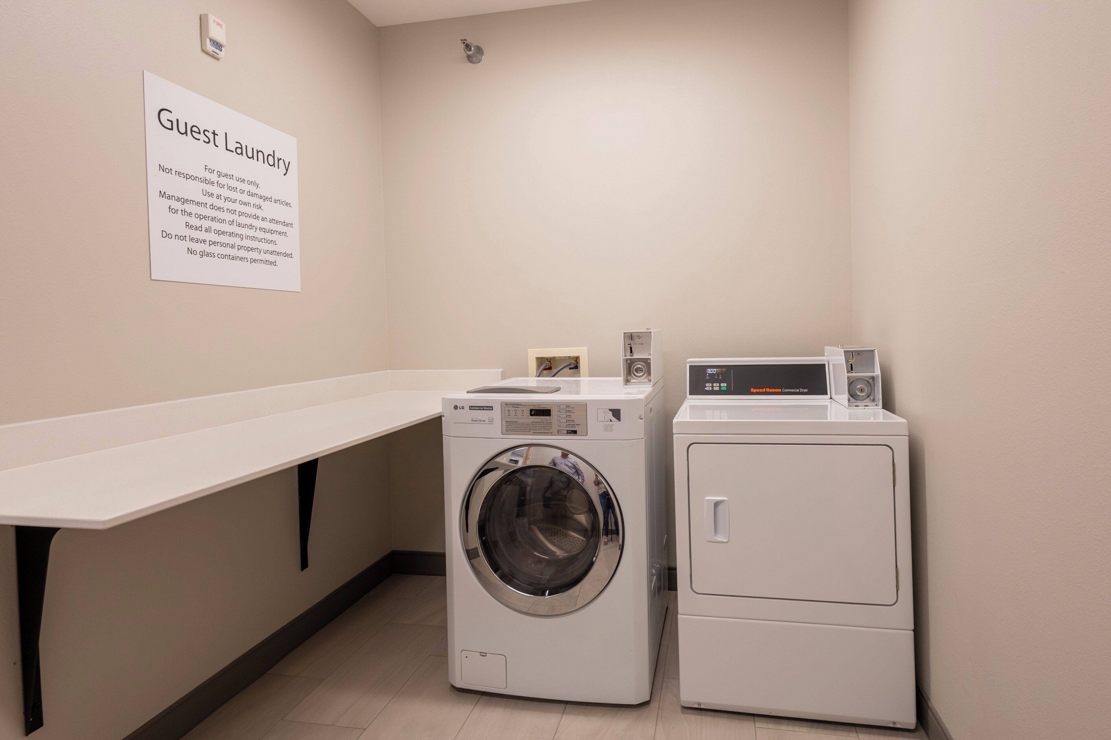 A guest laundry area with a sign indicating it's for guest use only, a washing machine, a dryer, and a white counter.