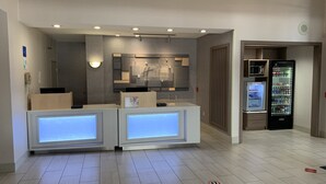 Een hotel receptie met een modern design, met een receptiebalie, een wandmontage display en een koelkast.
