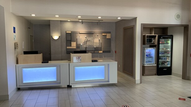 Een hotel receptie met een modern design, met een receptiebalie, een wandmontage display en een koelkast.