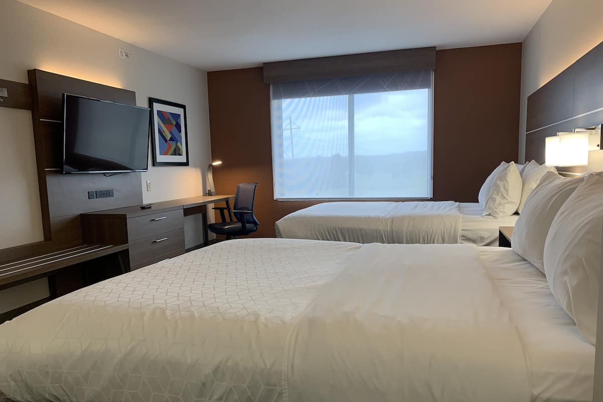Une chambre d’hôtel avec deux lits, un bureau avec une chaise, une télévision et une fenêtre donnant sur la ville.