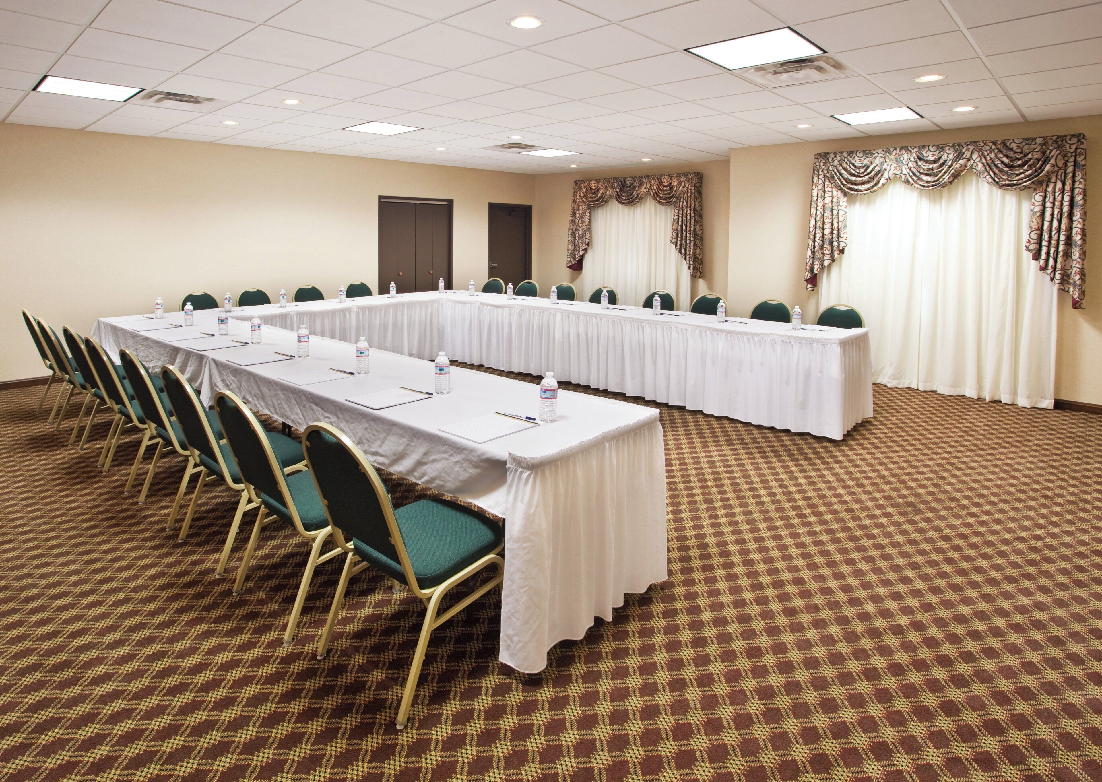A conference room with a long table, chairs, and a carpeted floor.