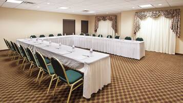 A conference room with a long table, chairs, and a carpeted floor.