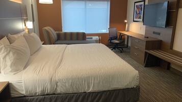 Una habitación de hotel con una cama grande, un escritorio, una silla, un televisor y una ventana.