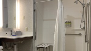 Een moderne badkamer met een douche, een wastafel met een handdoekrek, en een klein tafeltje.