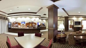 Eine Hotelhalle mit Rezeption, Sitzgelegenheiten und einem Fernseher.