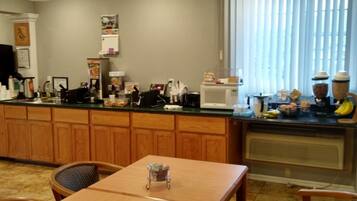 A kitchen with wooden cabinets, a microwave, a coffee maker, and a fruit bowl.