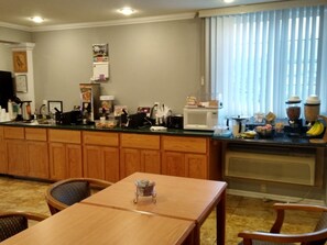 A kitchen with wooden cabinets, a microwave, a coffee maker, and a fruit bowl.