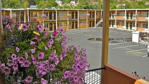 A hotel with a parking lot and a view of a building with balconies.
