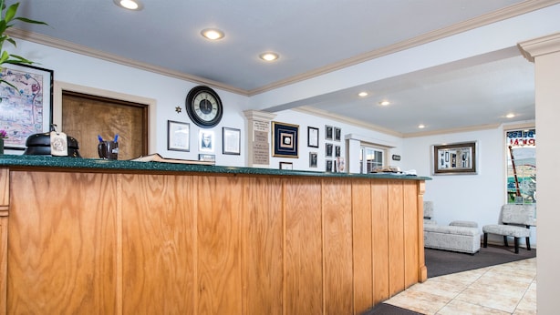 A reception area with a wooden counter, framed certificates, a clock, and a seating area with chairs.