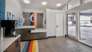 Uma área de recepção com design moderno, uma máquina de café e uma grande janela com vista para a rua.