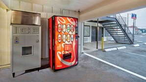 Uma máquina de vendas com o logotipo Coca-Cola, um freezer e um dispensador de bebidas da Coca-Cola.