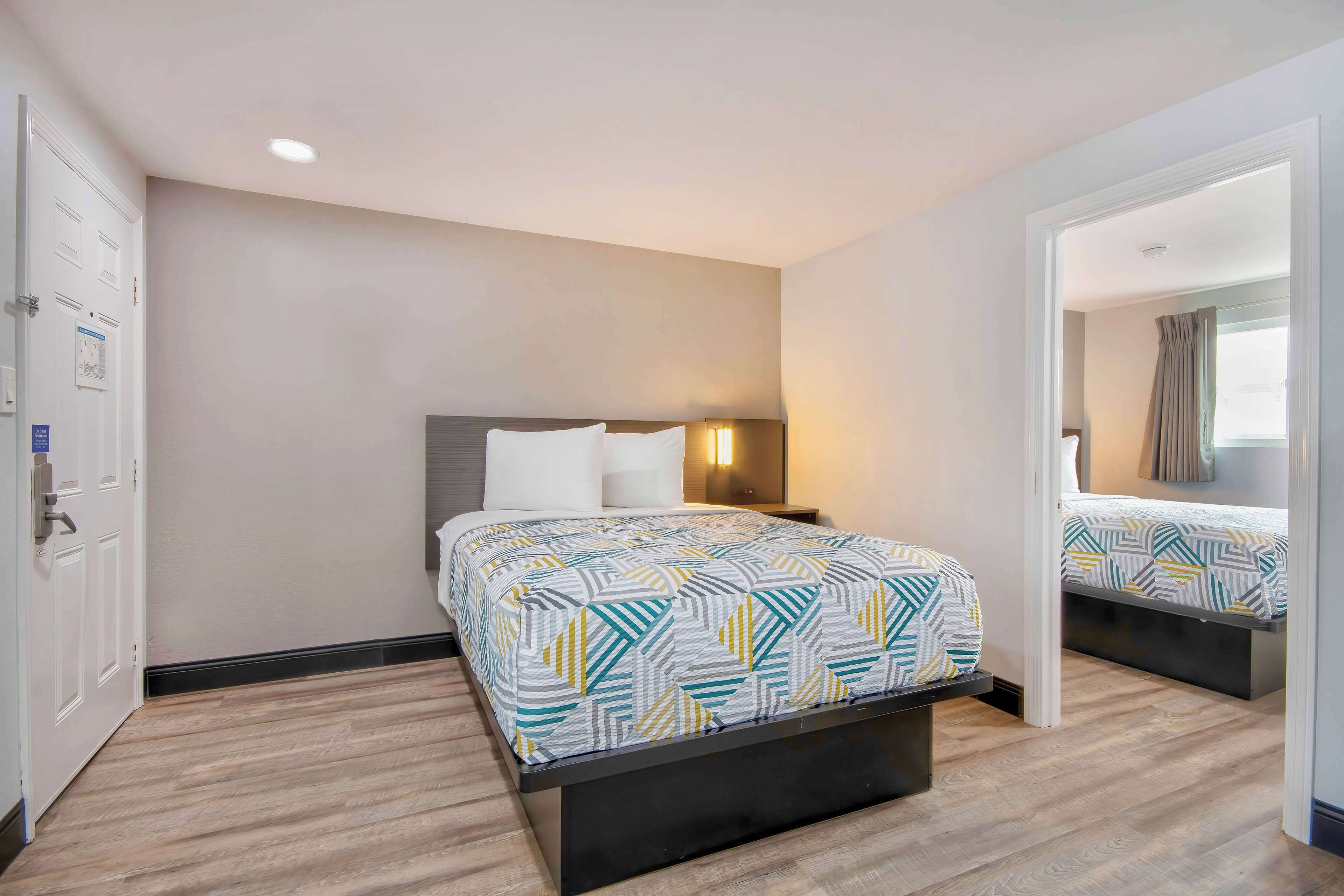 A hotel room with a bed, bedside table, and a nightstand.