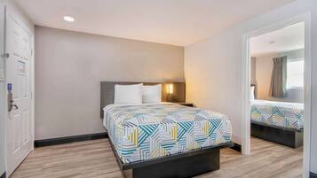 A hotel room with a bed, bedside table, and a nightstand.
