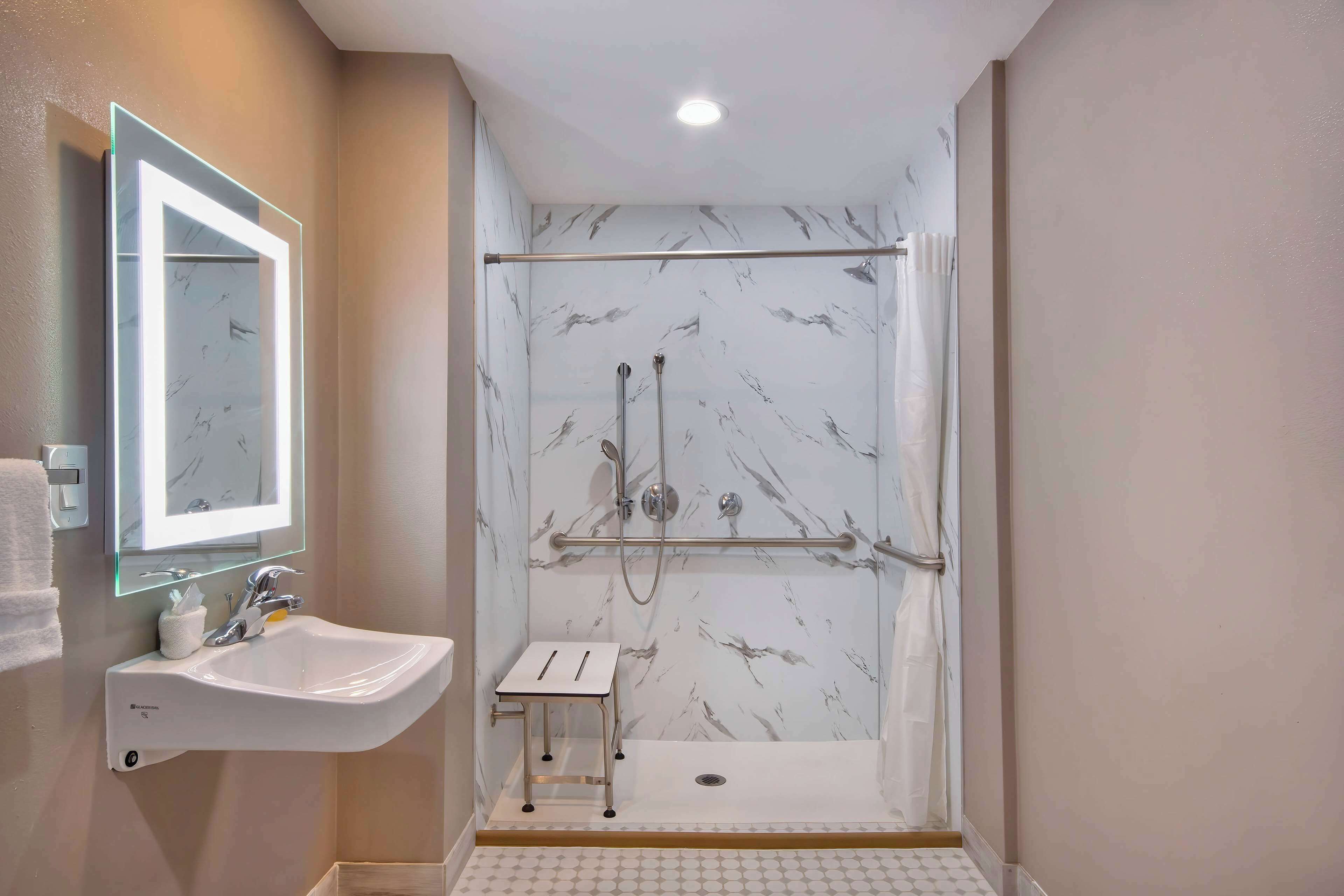 A bathroom with a white sink, a mirror, and a shower area with a glass door.