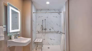 A bathroom with a white sink, a mirror, and a shower area with a glass door.