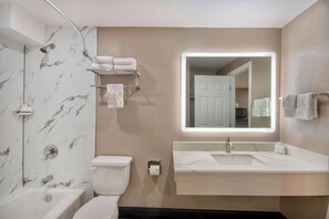 A modern bathroom with a bathtub, toilet, and a vanity with a mirror. - Studio 6 Eureka, CA – Old Town (Eureka)