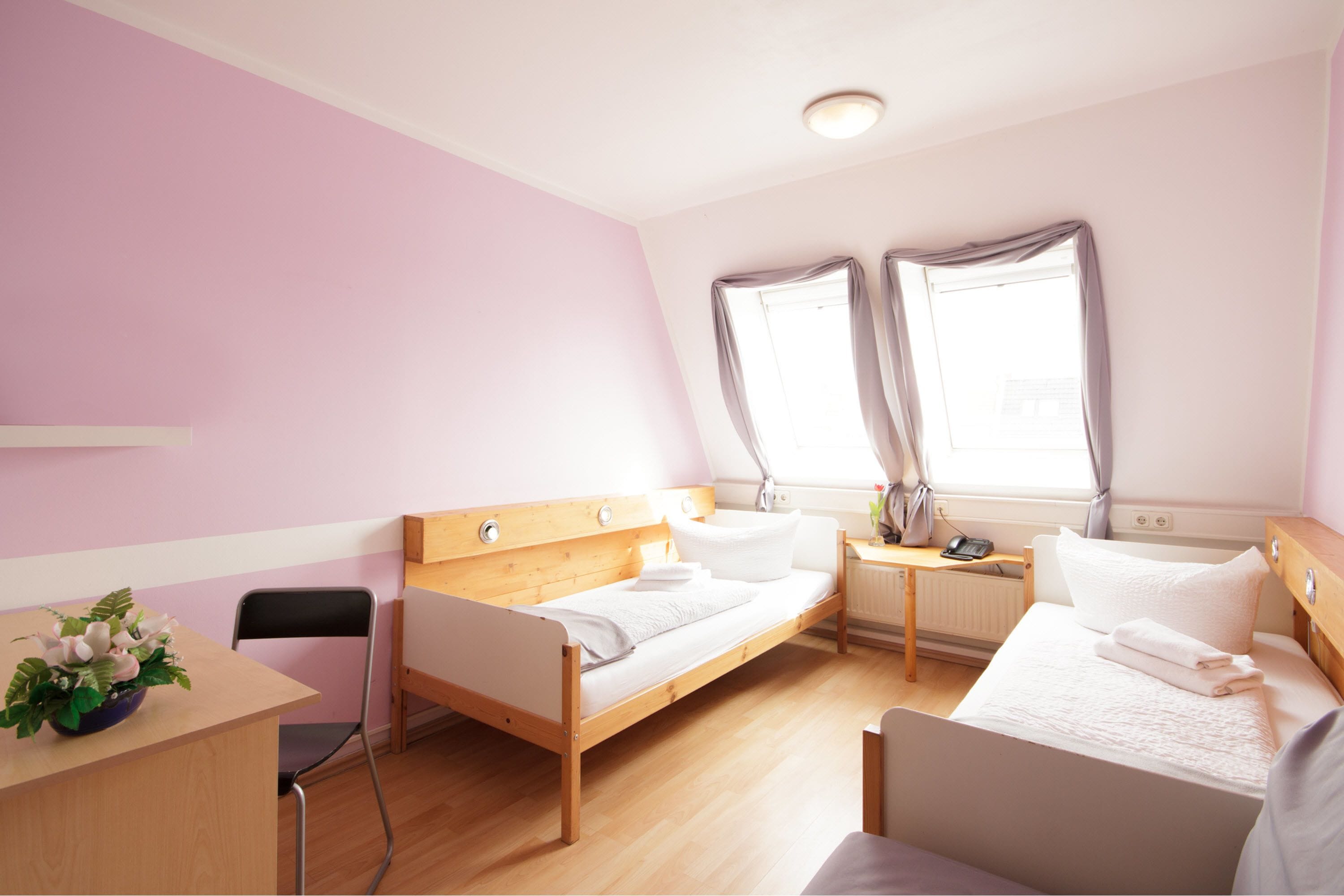 Una habitación con una cama, un escritorio, una silla y una mesita de noche con una lámpara.