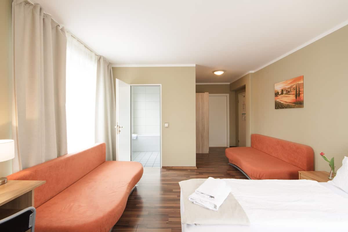 Ein Hotelzimmer mit zwei Betten, einem Schreibtisch und einem durchgegangenen Tür erkennbaren Badezimmer.