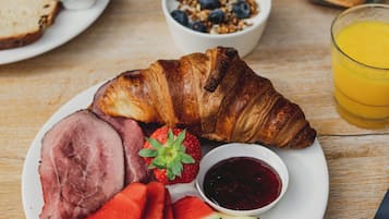 A breakfast plate with ham, croissant, strawberries, watermelon, and cucumber slices.