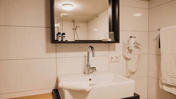 A bathroom with a white sink, a mirror, a towel, a hairdryer, and a phone.