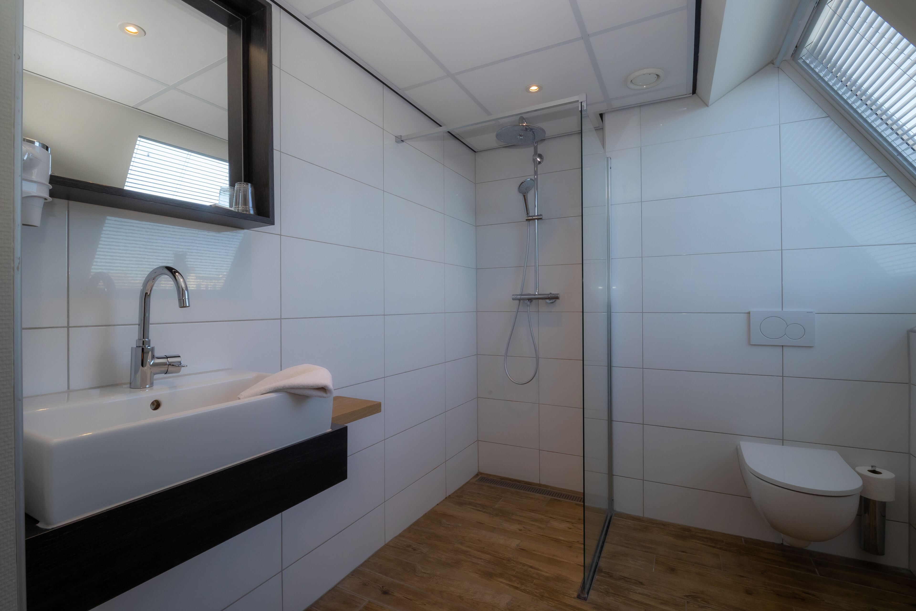 A modern bathroom with a white sink, mirror, and shower.