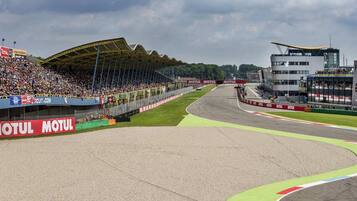 A race track with grandstands, a large covered area, and a modern building with a viewing platform.