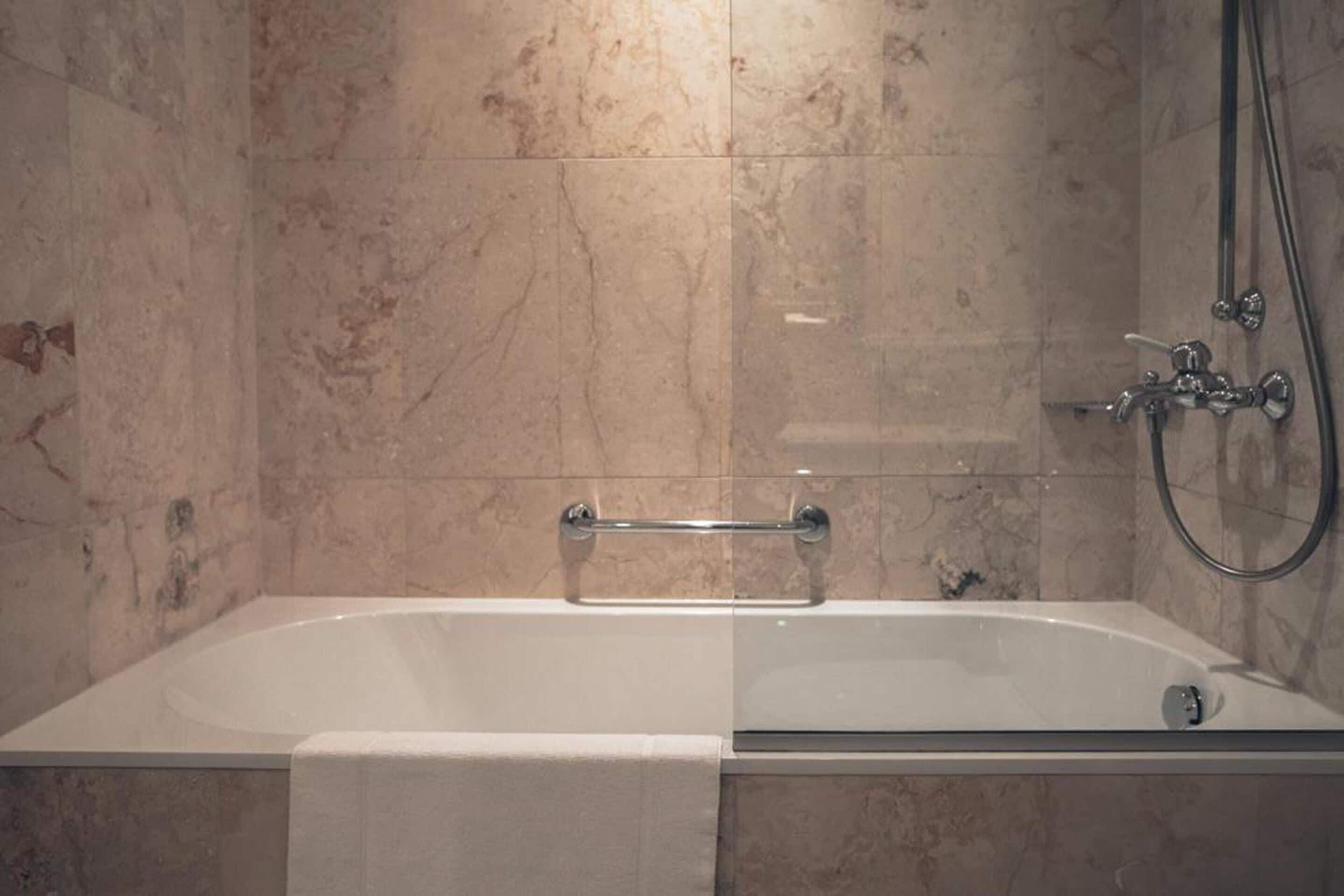 A bathroom with a bathtub, a shower, and a towel rack.