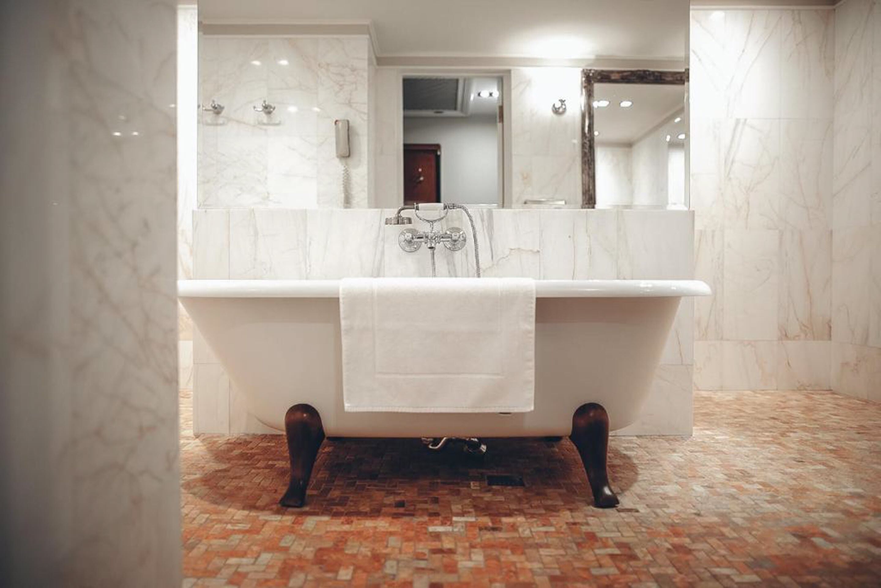 Ein modernes Badezimmer mit einer freistehenden Badewanne, einem großen Spiegel und Fliesenboden.