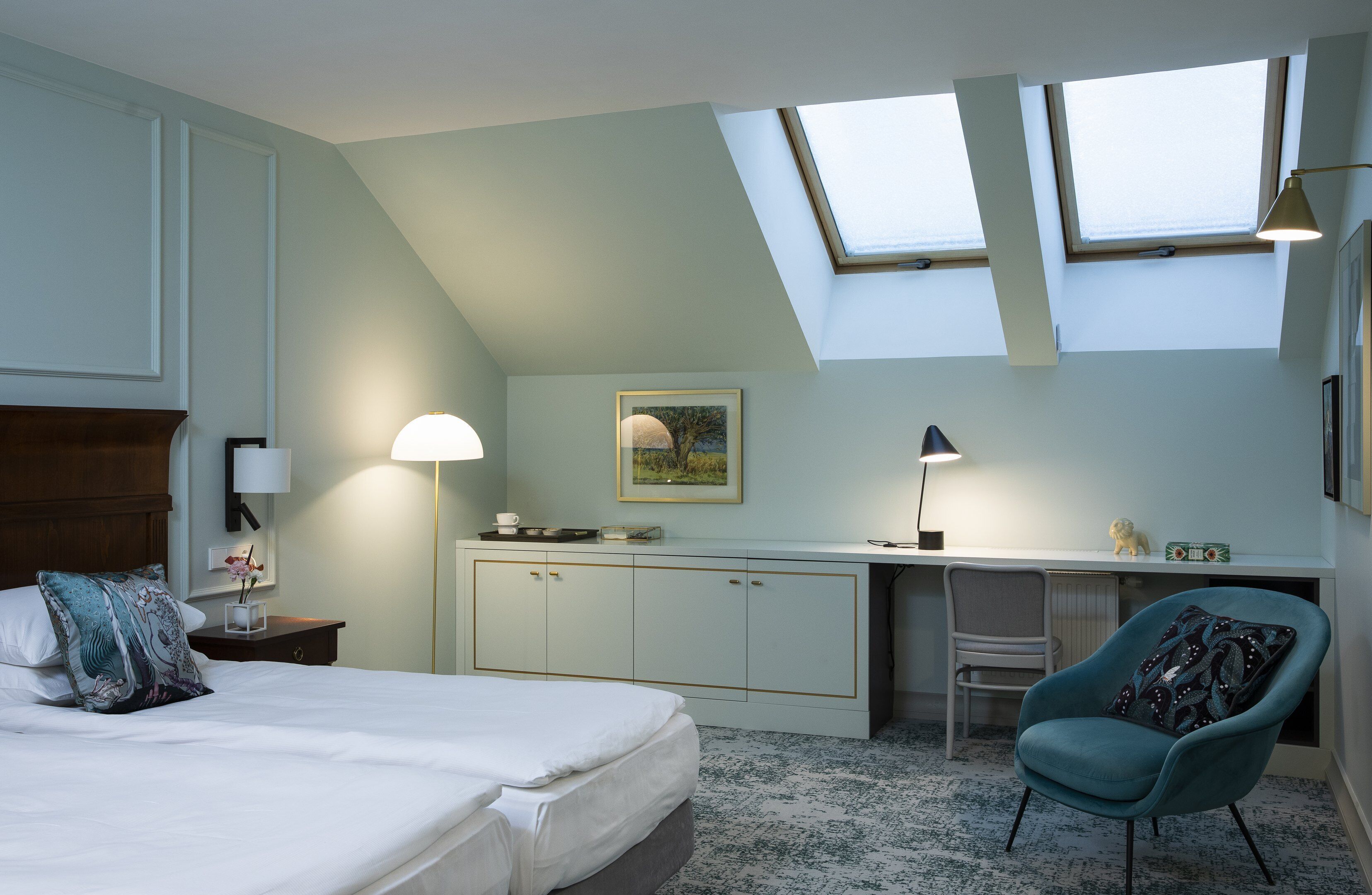 A bedroom with a bed, a desk, a chair, and skylights.