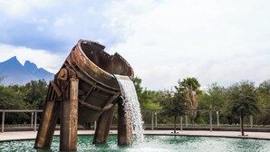 A water feature with a boat structure and a waterfall. - One Monterrey Aeropuerto (Apodaca)