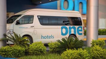 A white van with 'one hotels' branding parked in front of a building with large blue letters.