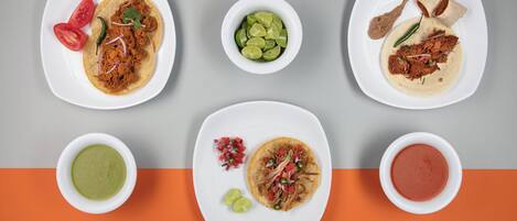 A top-down view of a table with various dishes, including tacos, a bowl of guacamole, and a bowl of salsa.