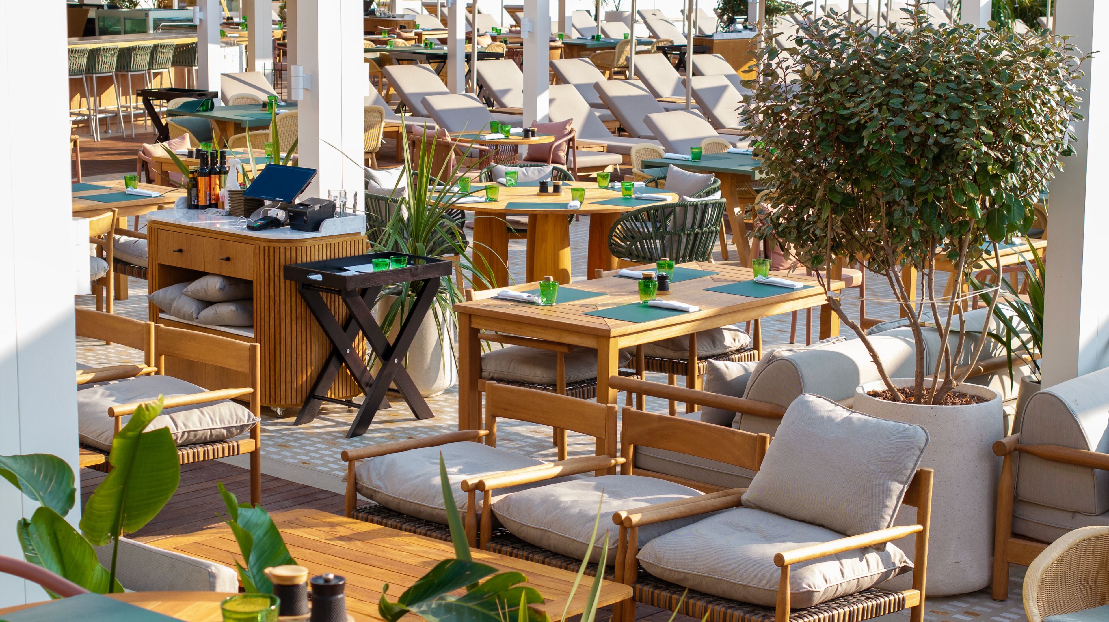 A rooftop bar with multiple tables and chairs, some with umbrellas.