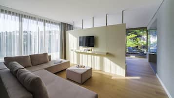 A modern living room with a sofa, ottoman, and a flat-screen TV mounted on a wall.