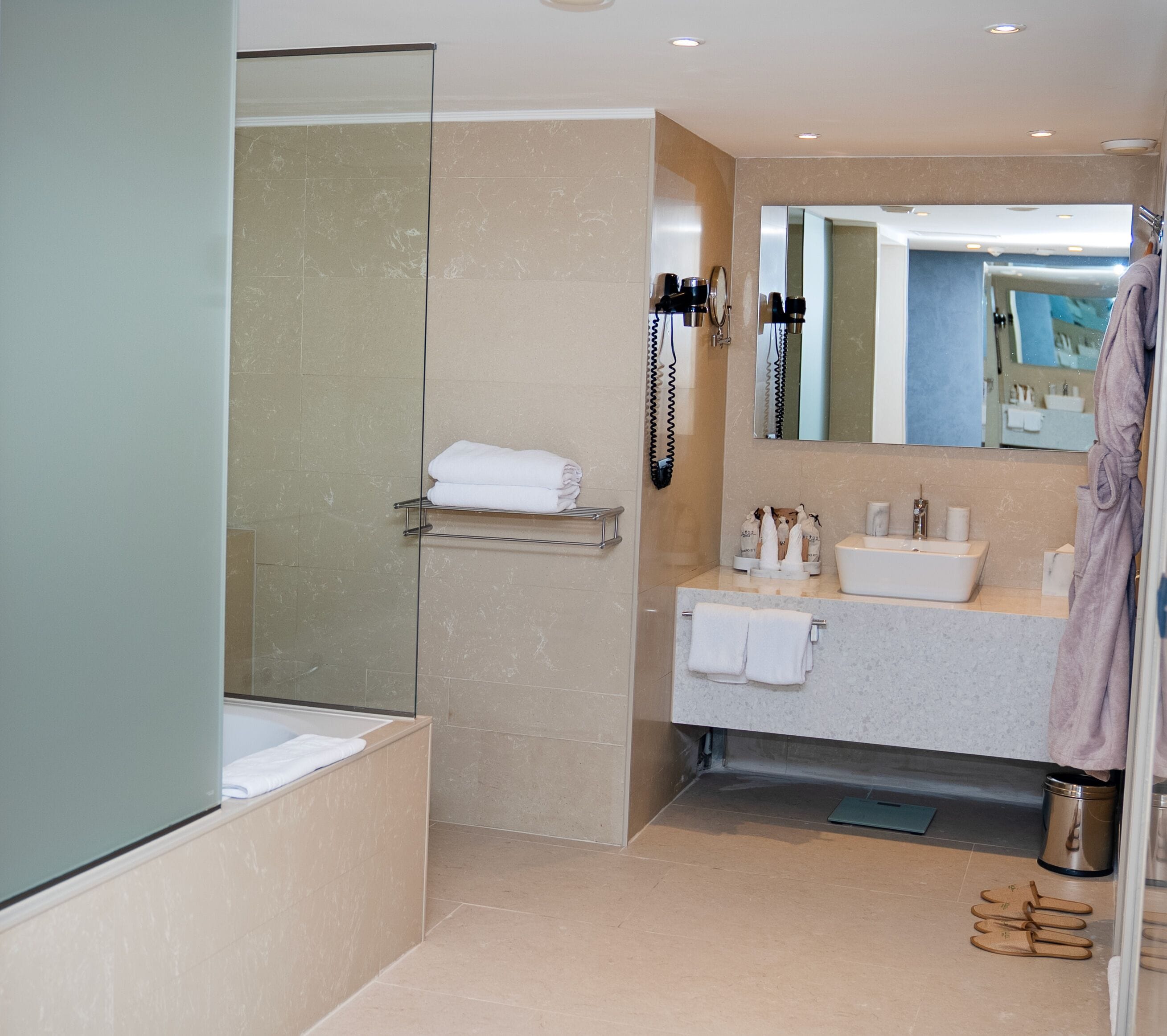 A modern bathroom with a glass-enclosed shower, a vanity with a sink, and a mirror.