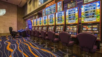 A row of slot machines with a 'JACKPOT' sign above them, arranged in a row with purple chairs in front.
