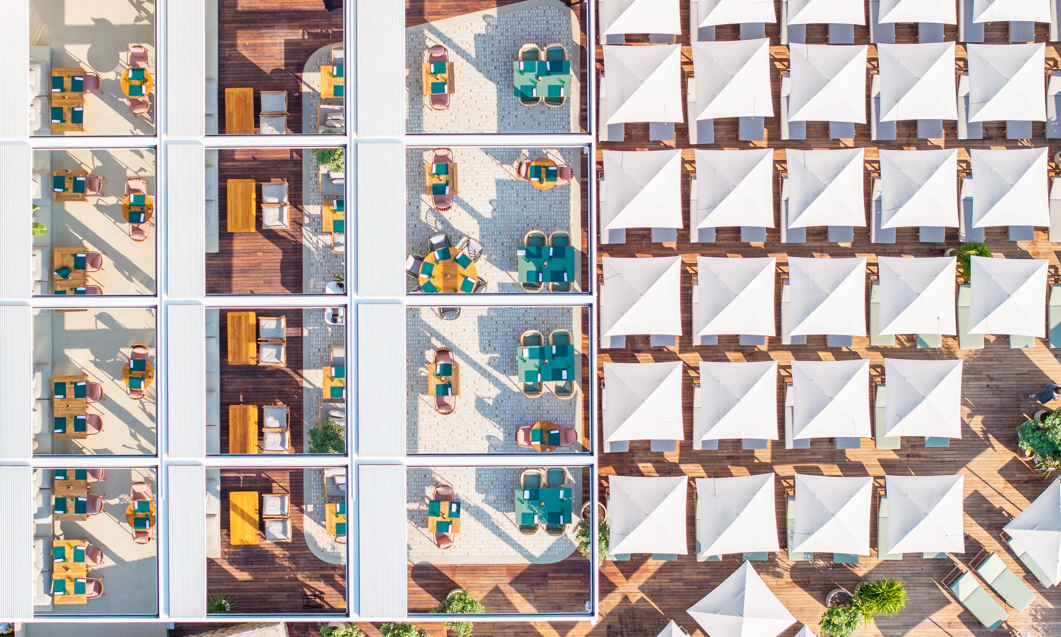Vue aérienne d’un hôtel doté de plusieurs espaces de restauration, de sièges en plein air et d’une variété d’agencements de tables et de chaises.