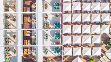 Vue aérienne d’un hôtel doté de plusieurs espaces de restauration, de sièges en plein air et d’une variété d’agencements de tables et de chaises.