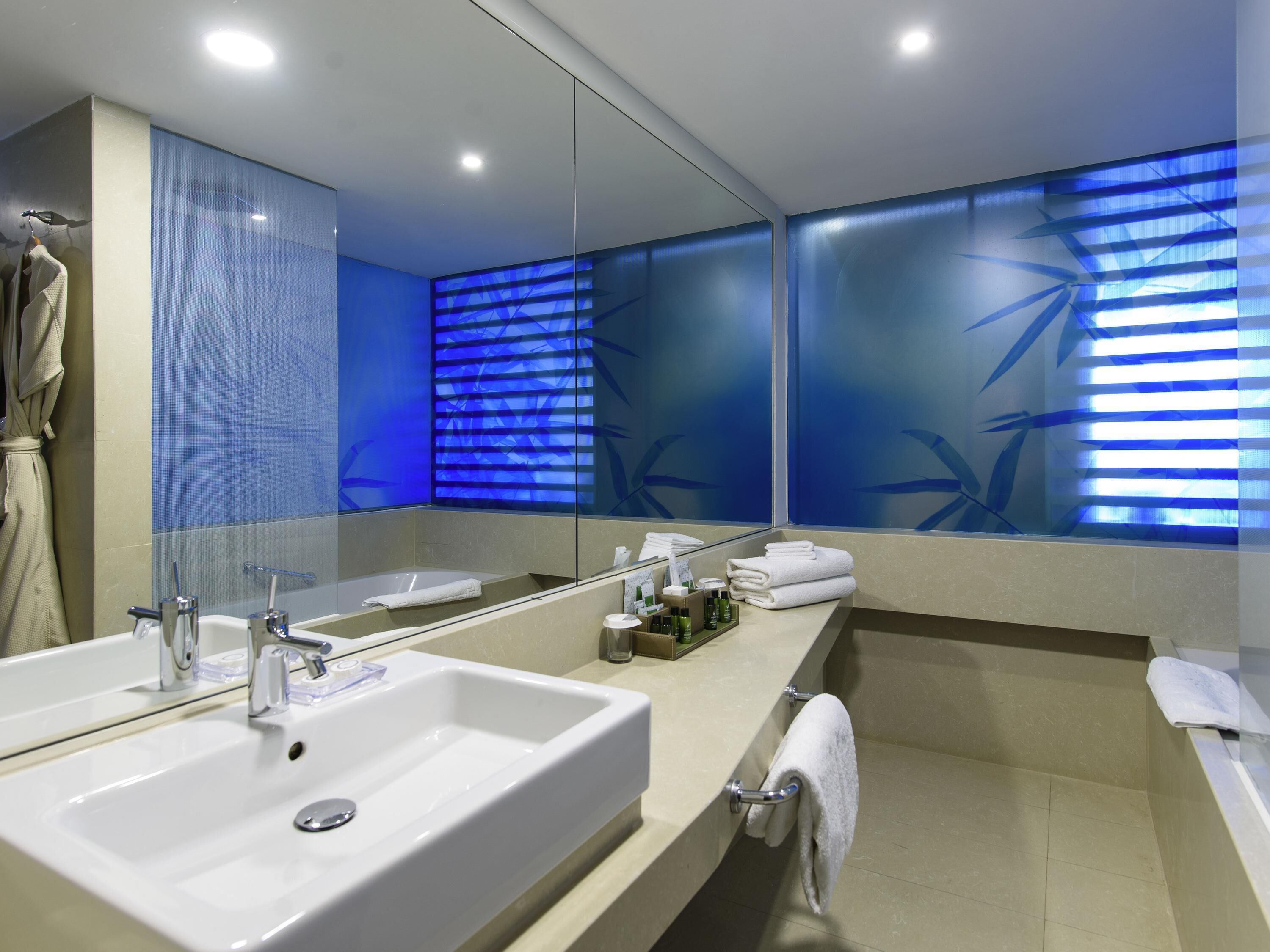 Une salle de bain moderne avec deux lavabos, un grand miroir et un porte-serviettes.