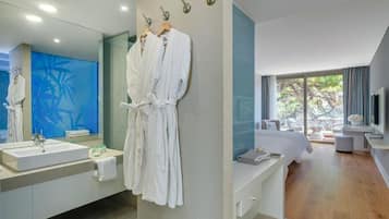 A modern bathroom with a large mirror, white sink, and two white robes hanging on hooks.